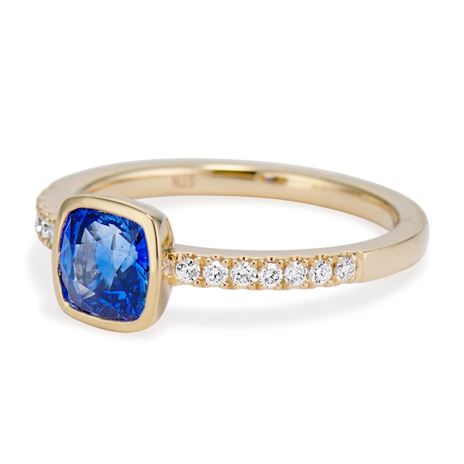Cushion Cut Blue Sapphire and Diamond Ring. bezel set sapphire and bead set diamond sides. band view