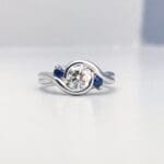 Embrace - Platinum with a diamond center and two accent sapphires.