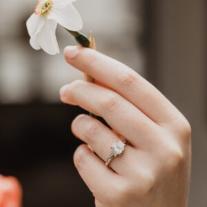 Emerald Cut Diamond ring On hand holding flower Social Media