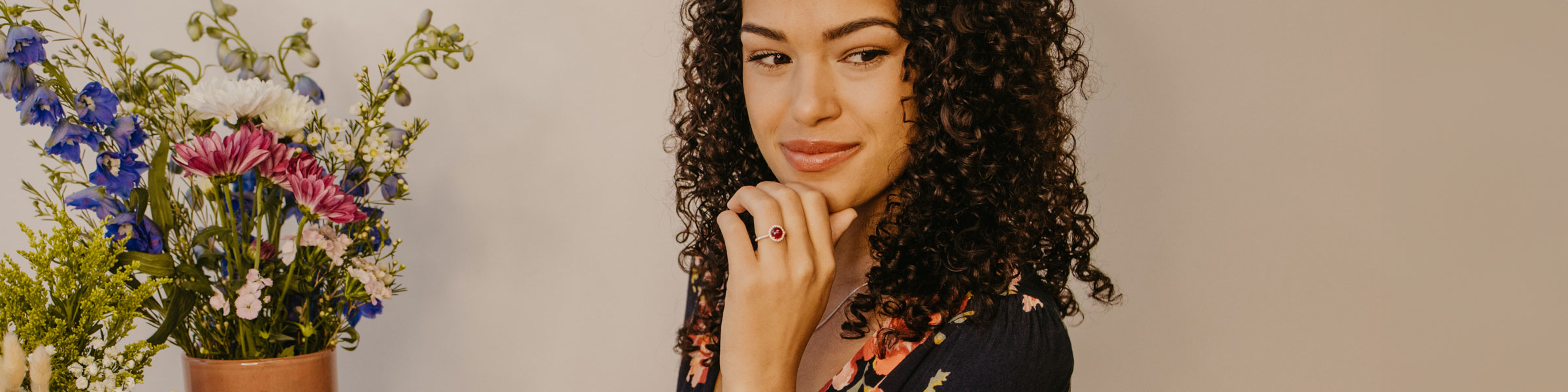 Woman with gemstone engagement ring and vase of colorful flowers