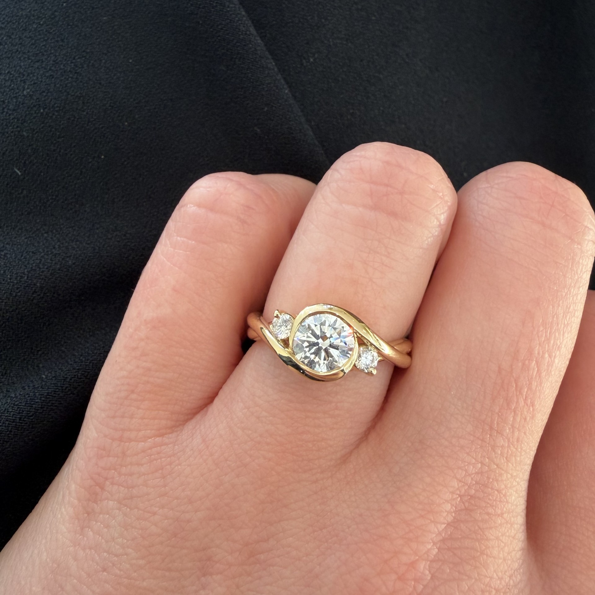 1.01ct round diamond bezel set engagement ring in 14K yellow gold with two smaller bezel-set diamonds