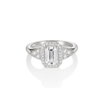 Platinum ring featuring a 1.05 carat emerald cut diamond with diamond halo and side trio diamond accents
