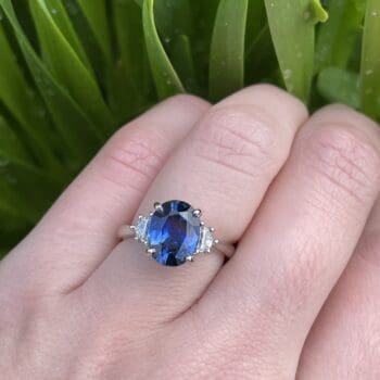 Platinum ring featuring an oval blue sapphire center and trellis Cadillac-cut diamond accents, size 6.5