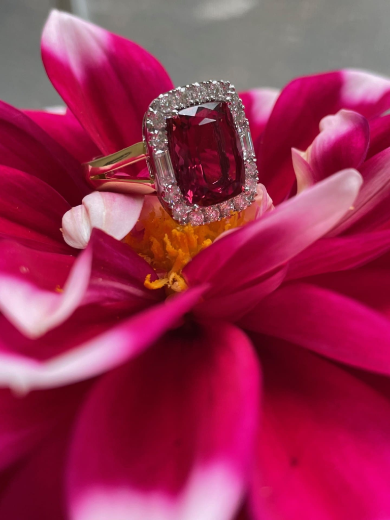 Elongated cushion-cut rubellite halo ring with 16 round and 2 baguette diamonds set in 18K two-tone gold