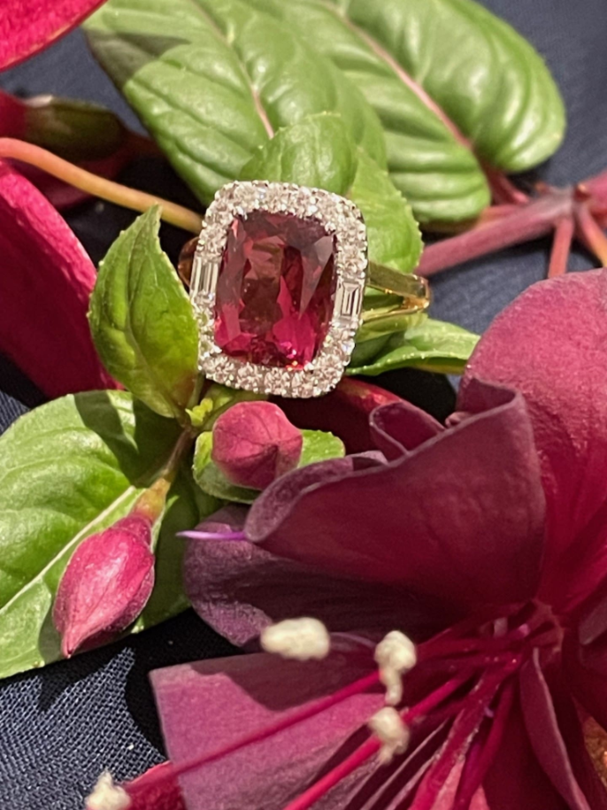 Elongated cushion-cut rubellite halo ring with 16 round and 2 baguette diamonds set in 18K two-tone gold