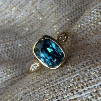 Teal blue zircon ring with elongated cushion cut gemstone accents set in 14K yellow gold, size 6.5