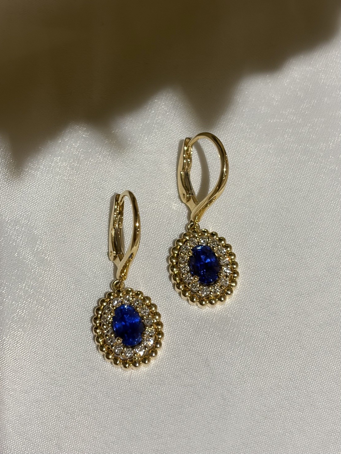 Oval blue sapphire and diamond earrings set in 18K yellow gold with French wire backs