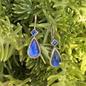 14K yellow gold drop earrings featuring pear-shaped moonstones with blue princess cut sapphire accents