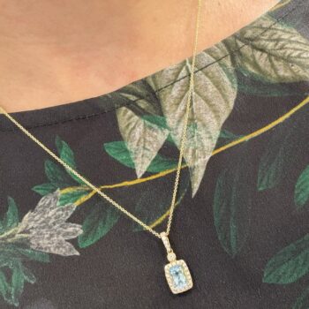 Aquamarine diamond halo necklace with light blue cushion-shaped aquamarine and 26 diamonds in 14K yellow gold on adjustable chain