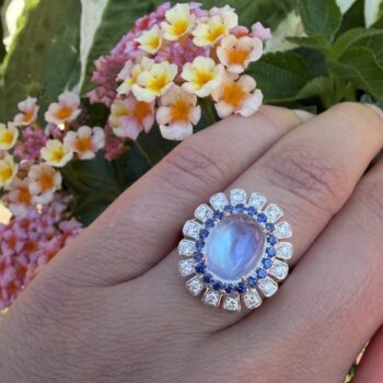 Double halo ring featuring moonstone center and surrounding sapphire gemstones